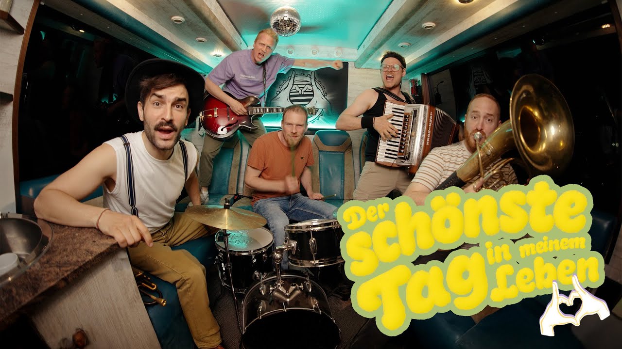 Standbild aus dem Musikvideo „Der schönste Tag in meinem Leben“: die Fäaschtbänkler spielen in einem türkis beleuchteten Tourbus mit Discokugel